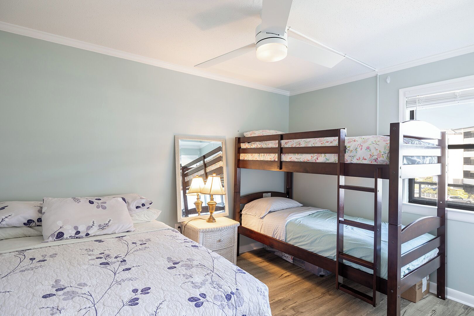 A bedroom with bunk beds, a bedside table with a lamp, and a window with blinds.