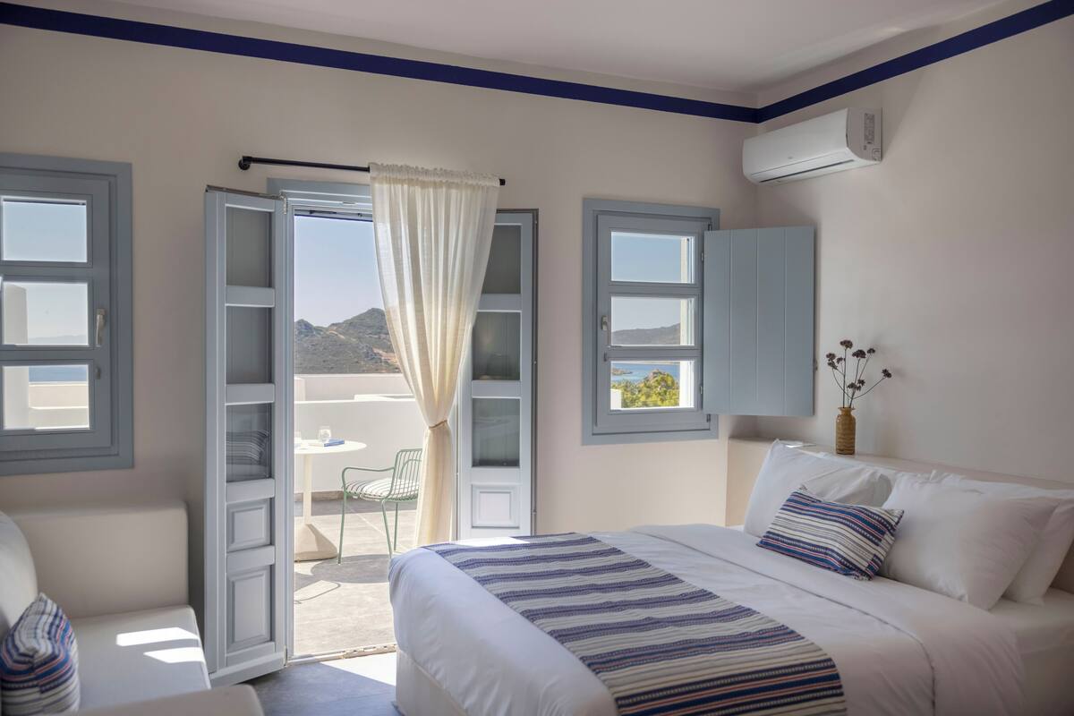 Een slaapkamer met een bed, raam, deur en een airconditioning.