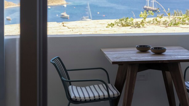 Een kamer met uitzicht op zee, een houten tafel en een stoel.