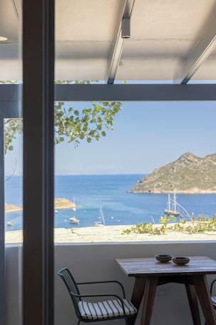 A room with a view of the sea, a wooden table, and a chair.