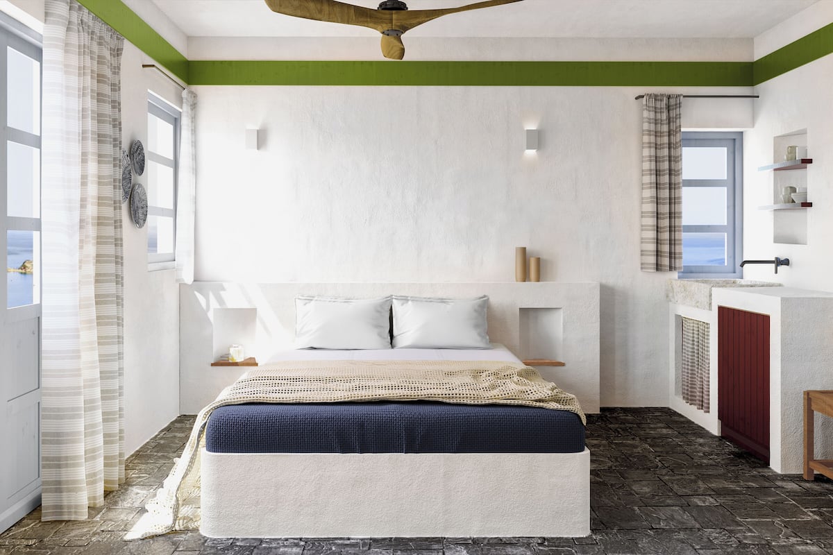 Een slaapkamer met een bed, nachtkastjes, een plafondventilator, een raam en uitzicht op zee.