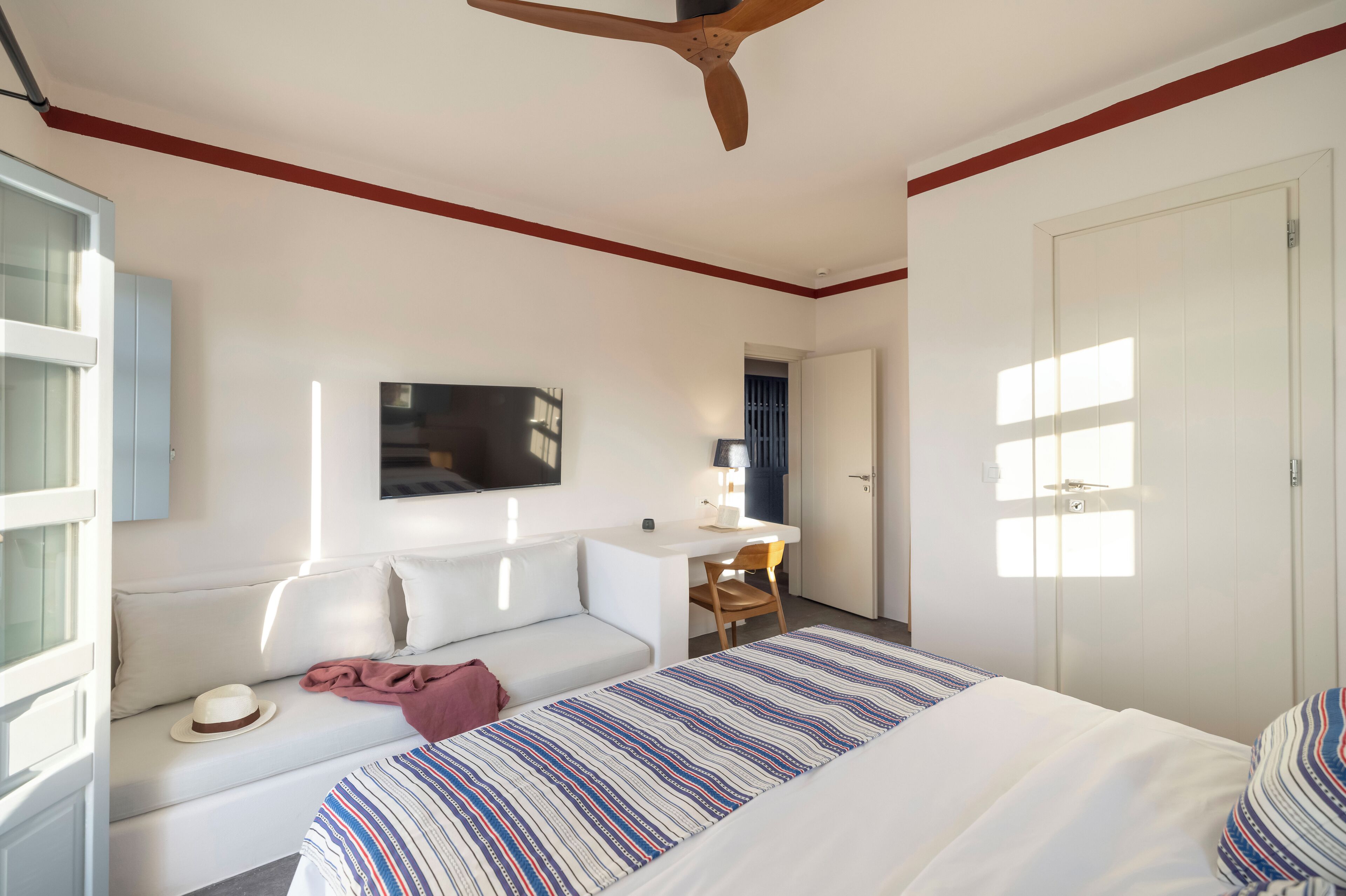 A bedroom with a bed, a desk, a sofa, a TV, and a wardrobe.