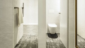 Een moderne badkamer met een douche, toilet en een handdoekhouder.