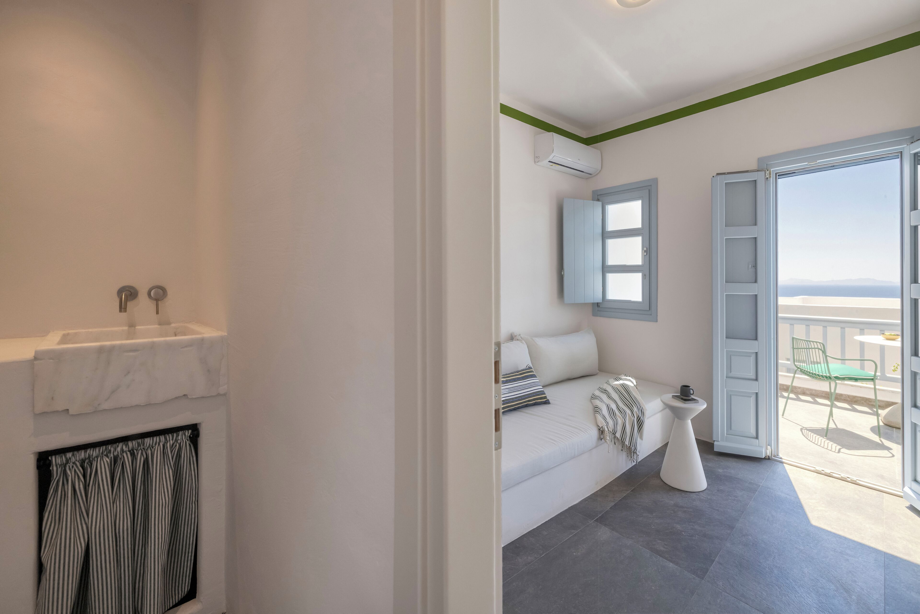 Un baño moderno con un lavamanos de mármol, una cortina de ducha a rayas y una bañera blanca.