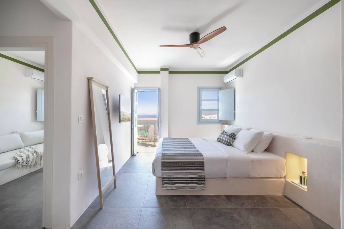 Een moderne slaapkamer met een bed, een plafondventilator, een raam en uitzicht op de omgeving.