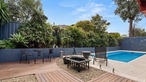 Ein Garten mit Schwimmbad, Holzterrasse und Sitzbereich.