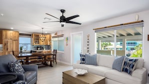 A modern living room with a sofa, coffee table, and a dining area with a wooden table and chairs.