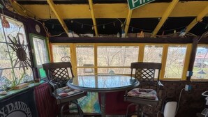 Un interior acogedor con una mesa redonda de vidrio rodeada de sillas, un cartel de Pinnacle y vistas a través de grandes ventanales.