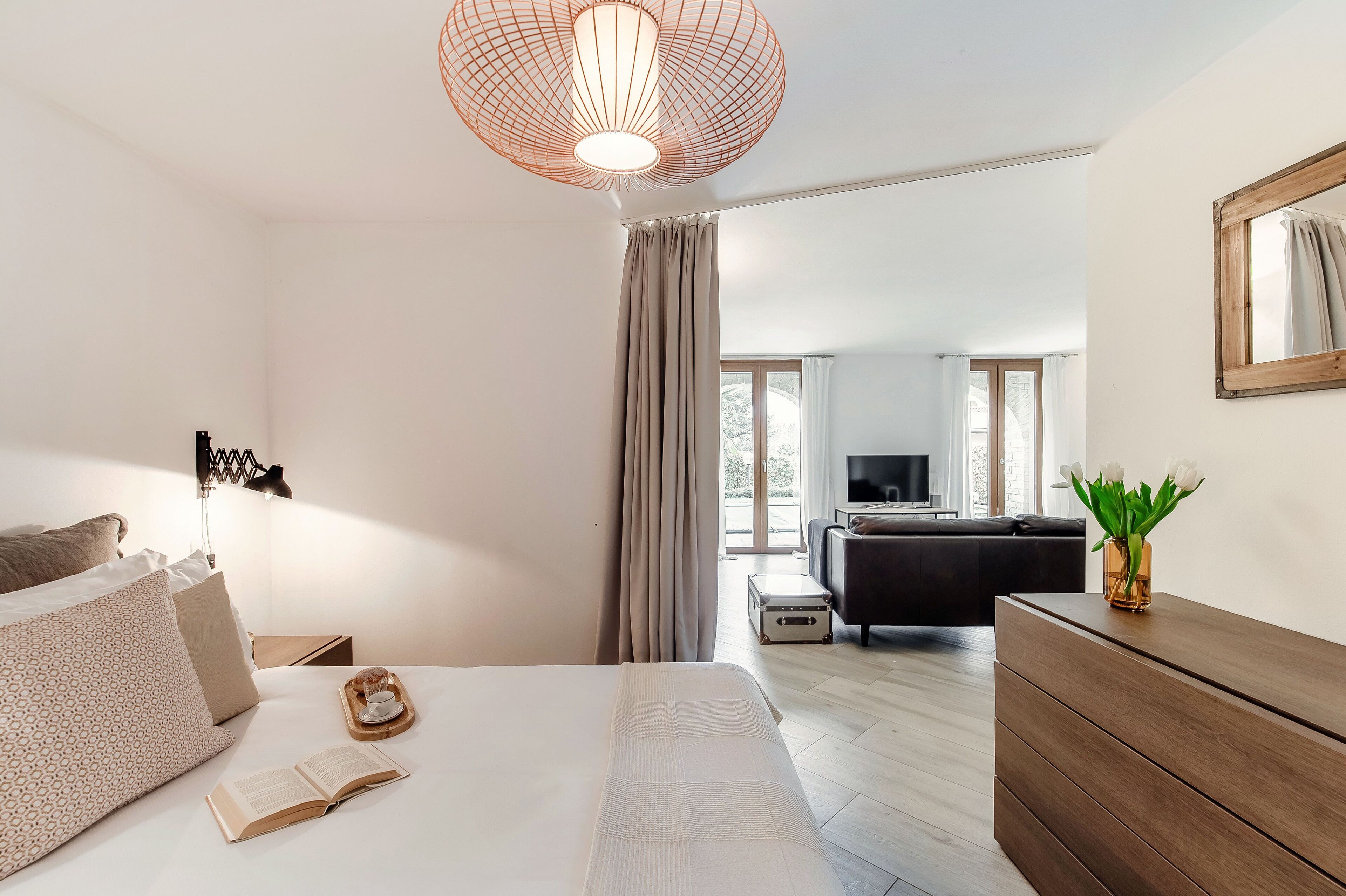 Ett modernt hotellrum med en stor säng, en byrå i trä, en TV och utsikt över omgivningarna.