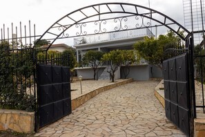 Uma entrada fechada com um caminho de pedra que leva a um edifício com varanda.