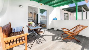 A covered patio with a table and chairs, a wooden bench, and a folding chair.