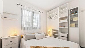A bedroom with a bed, bedside tables, a wardrobe, and a window with curtains.
