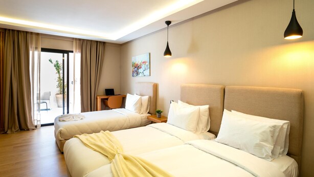 A hotel room with two beds, a desk, a chair, and a painting on the wall. - Hotel Unico Maarif (Casablanca)