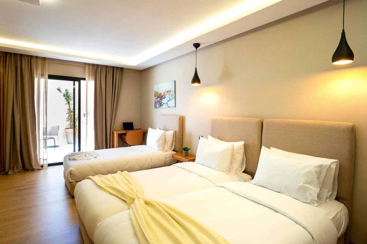 Ein Hotelzimmer mit zwei Betten, einem Schreibtisch, einem Stuhl und einem Bild an der Wand.