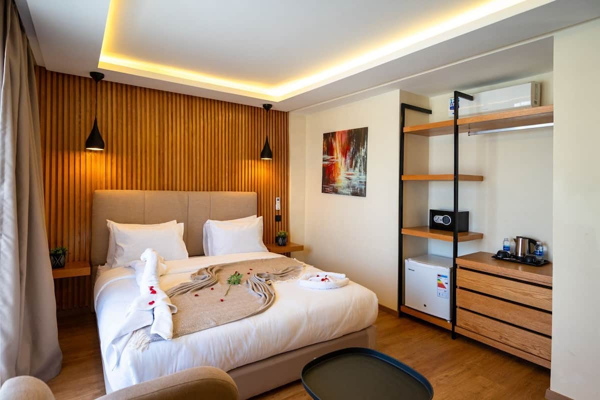 Ein modernes Hotelzimmer mit einem großen Bett, Nachttischlampen, einem Schreibtisch mit Computer und einem Kleiderschrank.