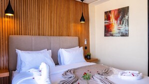 A hotel room with a large bed, wooden panel wall, modern pendant lights, and a painting on the wall. - Hotel Unico Maarif (Casablanca)