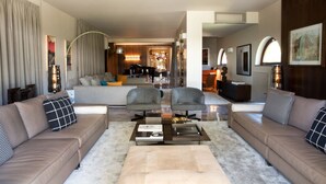 Una sala de estar moderna con un conjunto de sofá, sillones, una mesa de centro y un comedor al fondo.