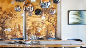 Un comedor con una larga mesa, varias sillas y un mural grande en la pared.