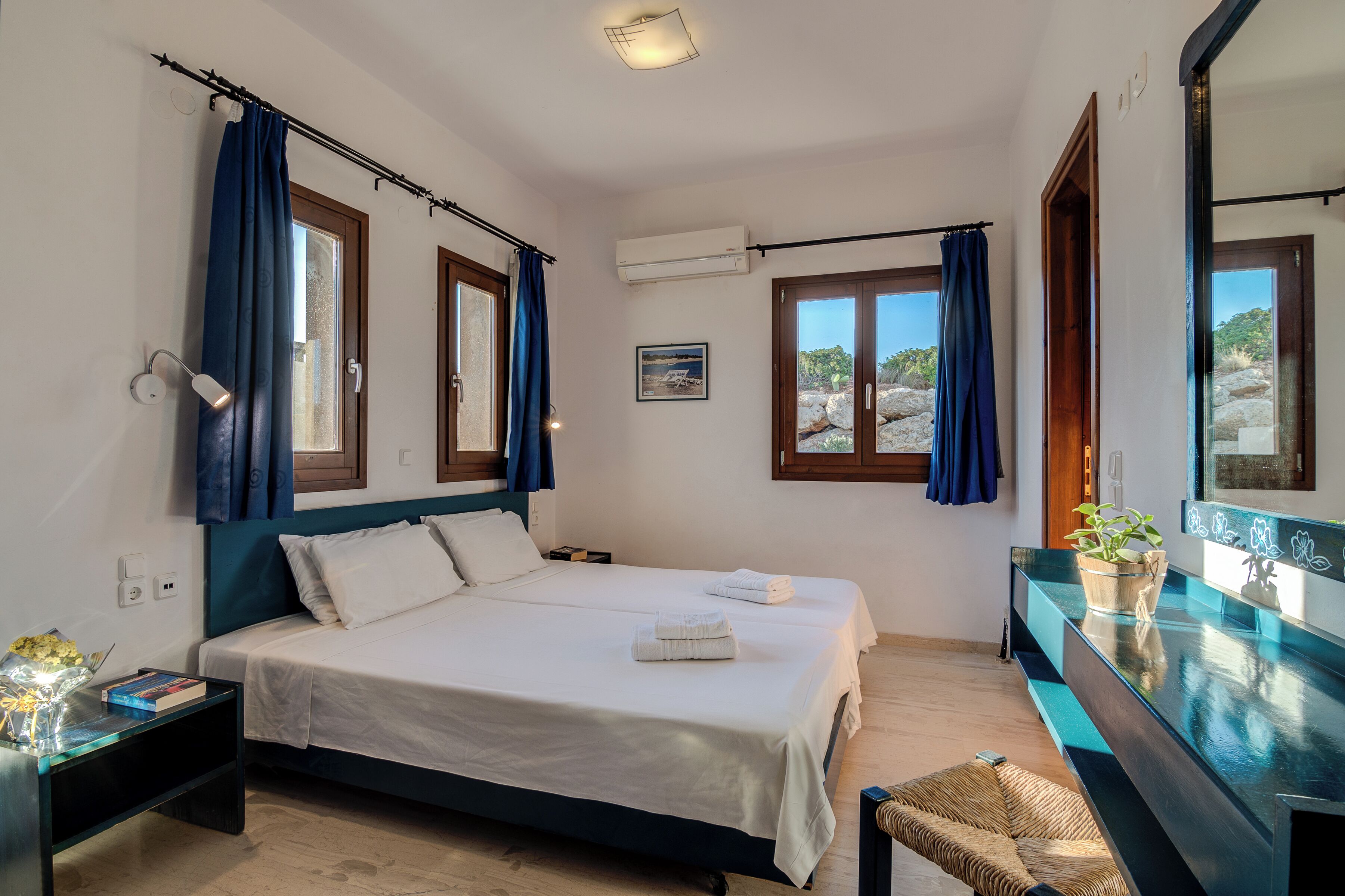 A bedroom with a bed, bedside tables, a mirror, and a window with curtains.