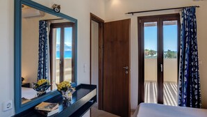 Un dormitorio con un espejo grande, una mesita de noche con libros y vistas al balcón.