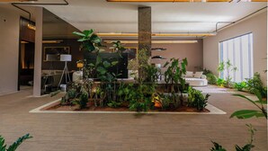 Een modern interieur met een plantenhoek, een bank en een lamp.