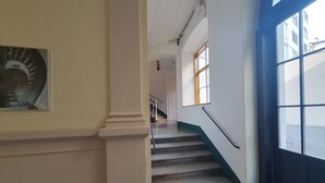 Una scala con corrimano, una porta con finestra e un muro con un quadro incorniciato.