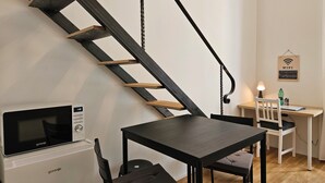 Una cucina moderna con forno a microonde integrato, un'area pranzo con tavolo e sedie, e una scala con gradini in legno e ringhiere in metallo.