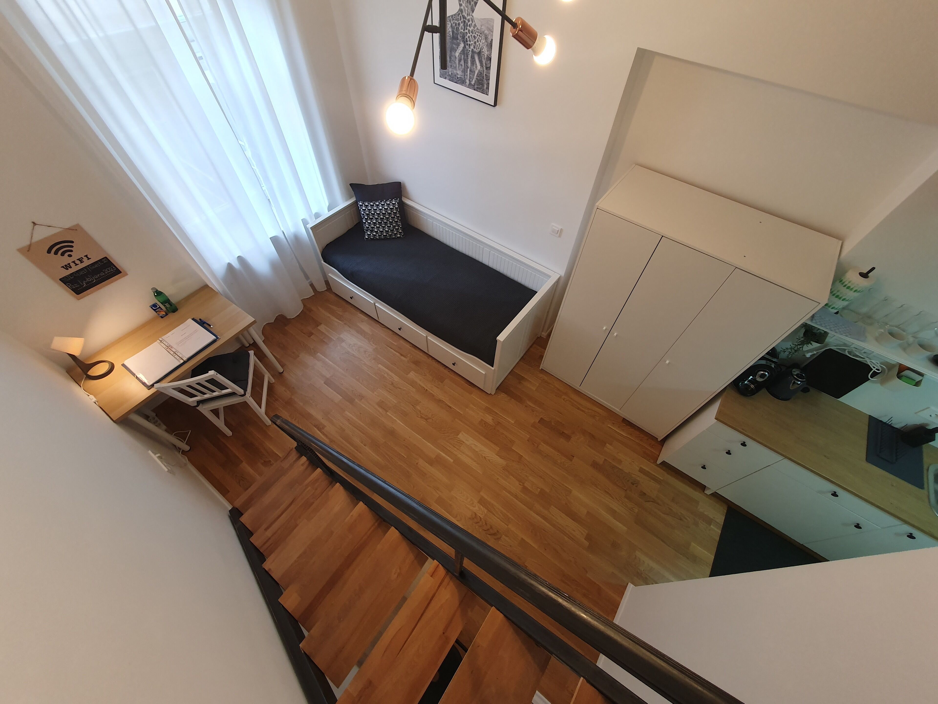 Ein kleines Zimmer mit Bett, Schreibtisch und einer Küchenzeile.