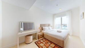 Une chambre d’hôtel moderne avec un grand lit, un bureau avec un miroir, une petite table de chevet et une fenêtre avec des rideaux.