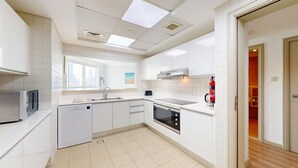 Una cucina moderna con mobili bianchi, lavastoviglie, forno e microonde.