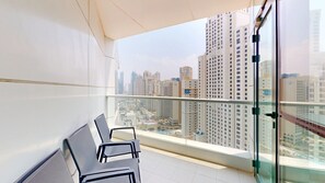 A balcony with a view of a cityscape, including high-rise buildings and a blue sign.