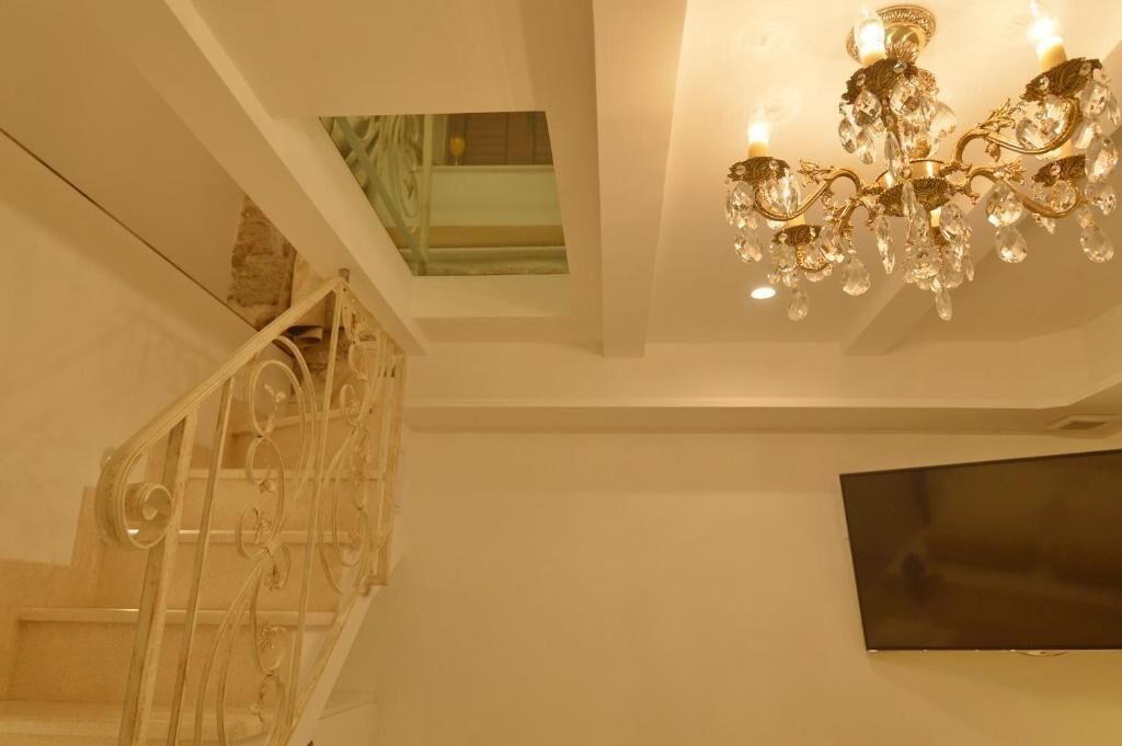 Eine Treppe mit schmiedeeisernem Geländer, einer Kristalllüster und einem an der Wand befestigten Flachbildfernseher.