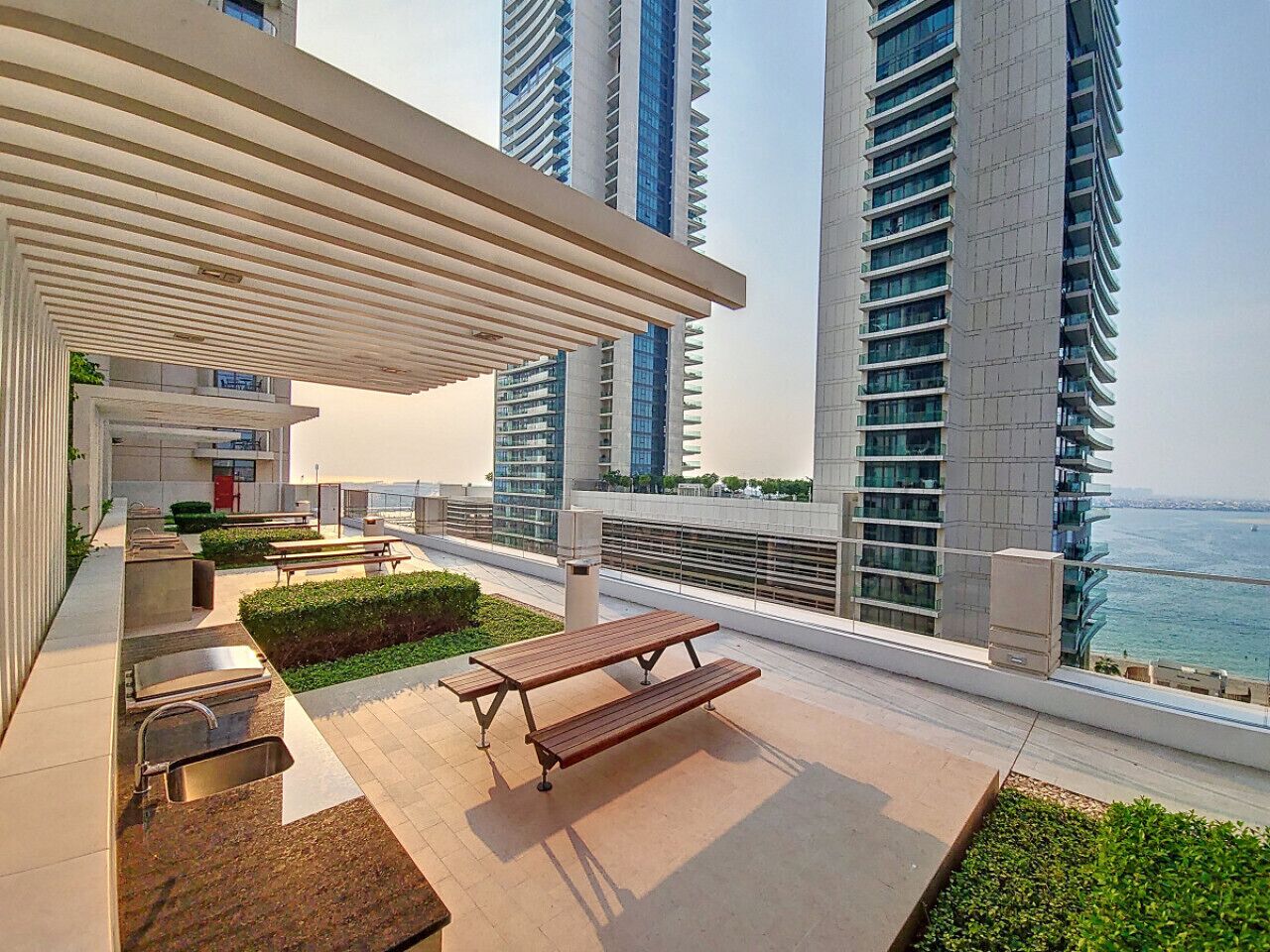 A rooftop terrace with a pergola, outdoor seating, and a view of the sea.