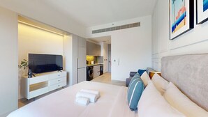 A modern hotel room with a large bed, a flat-screen TV, a small kitchen area, and a bathroom visible through an open door. - Mag 980 - Cosy Studio with City Views in Meydan (Meydan)