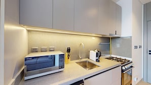 A modern kitchen with a built-in microwave, a gas stove, a sink, and a knife block. - Mag 980 - Cosy Studio with City Views in Meydan (Meydan)