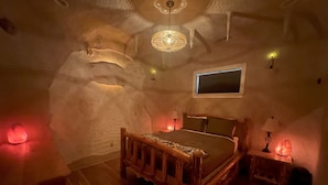 Un dormitorio con cama de madera, una mesita de noche, una lámpara de pared y un aplique de techo.
