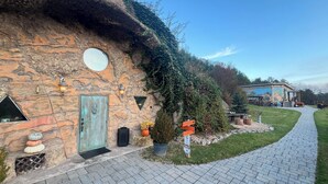 Un edificio de piedra con tejado de paja, una ventana redonda y un camino que lleva a un porche.