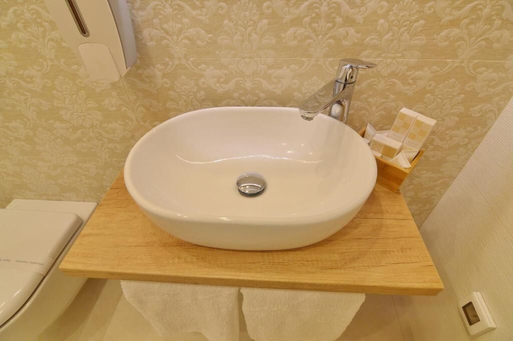 Une salle de bain avec un lavabo blanc posé sur un plan de travail en bois, un miroir et un porte-serviettes.
