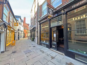 A street with shops, including a jewelry store with a sign that says 'Fossils Crystals.'