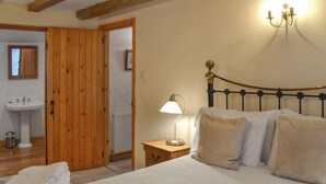 Une chambre à coucher avec un lit, une lampe de chevet et une porte en bois donnant accès à une salle de bain.