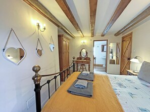 Un dormitorio con una cama de madera, un aparador, un espejo y una mesita de noche.