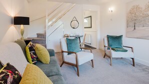 Un salon moderne comprenant un canapé, deux fauteuils, une table basse et un escalier menant à une autre pièce.