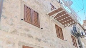 A multi-story building with stone walls and wooden shutters on the windows.