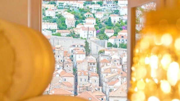 A view through a window of a cityscape with buildings and greenery.