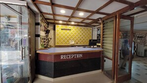 Ein Empfangsbereich mit einer Theke, auf der „RECEPTION“ steht, einer Wand mit gelbem Muster und einer Holzbalkendecke.