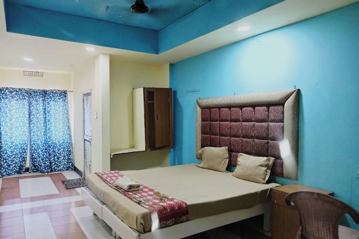 A bedroom with a large bed, a wardrobe, a ceiling fan, and a bathroom with a shower curtain.