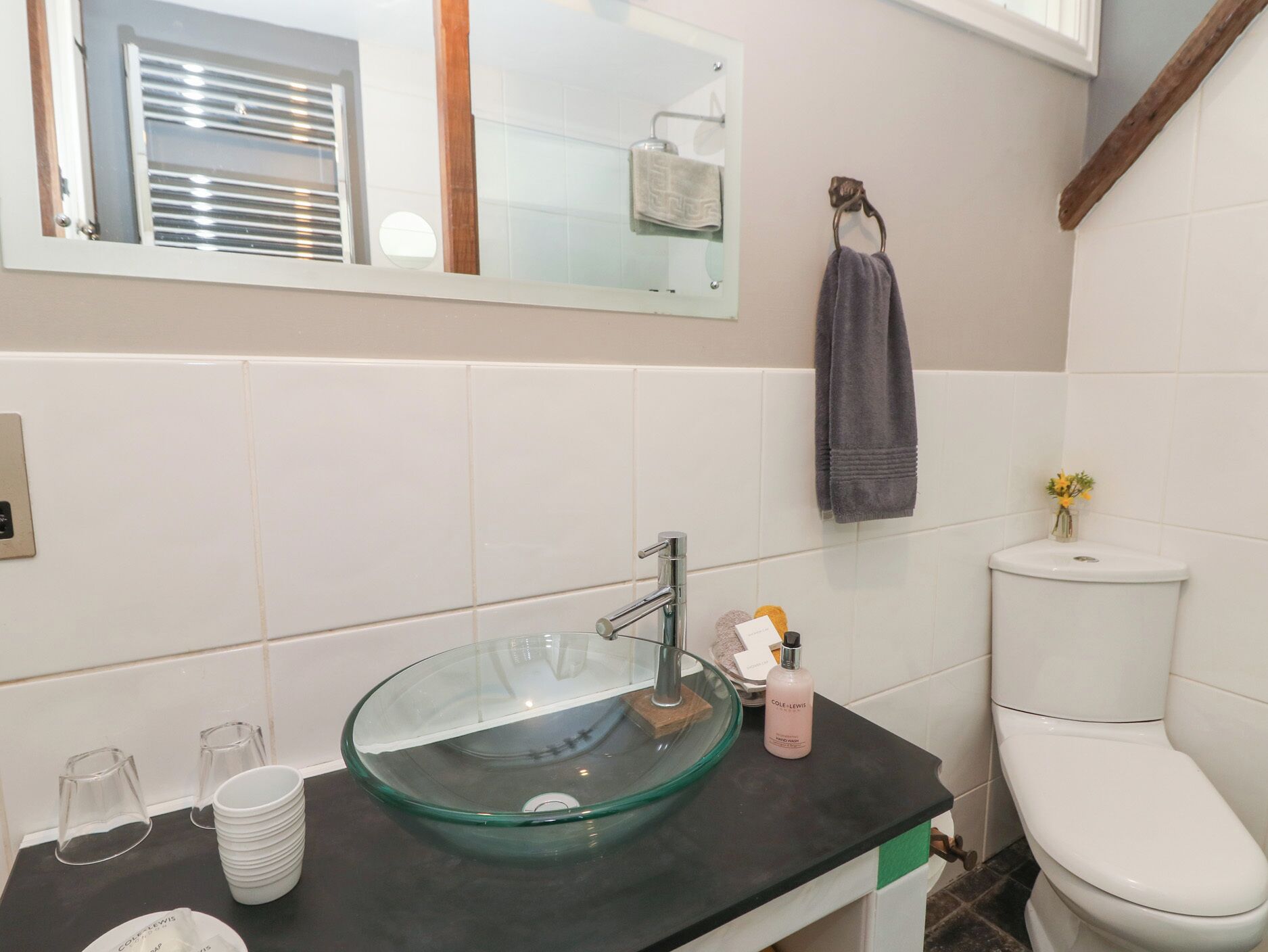 Ein Badezimmer mit einem Waschbecken aus Glas, einer Toilette und einem Spiegel.