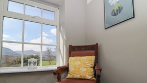 A corner room with a large window offering a scenic view of hills and a tree. - Cantref House Top Floor (Brecon)