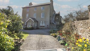 A large, two-story building with a gravel driveway and a stone wall on one side. - Cantref House Top Floor (Brecon)