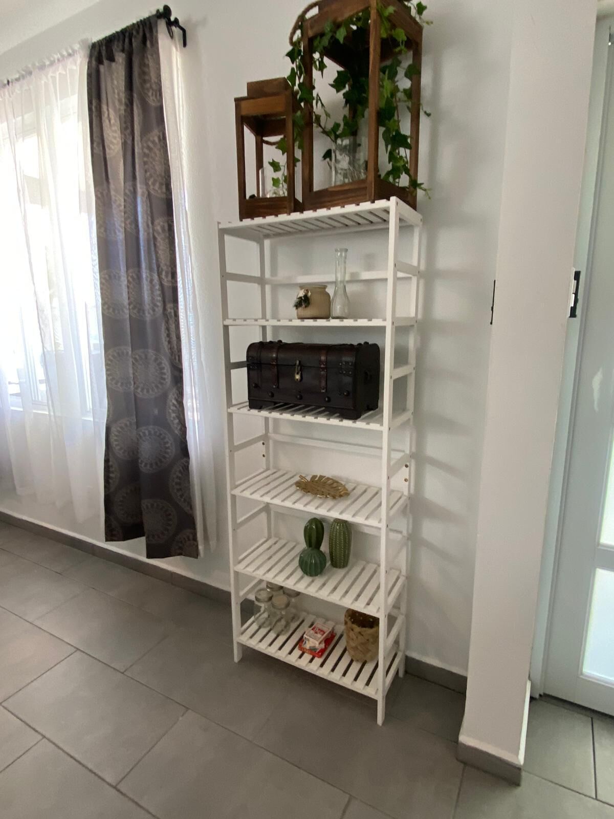 Une étagère blanche, ornée d’objets décoratifs, et une valise.